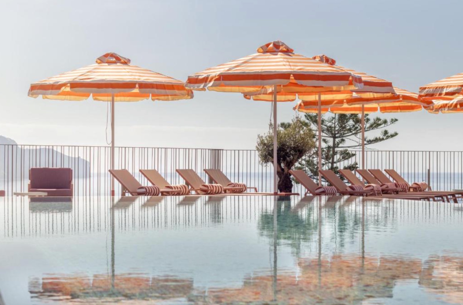 Chapéus de sol às riscas e espreguiçadeiras junto à piscina no NEXT - by Savoy Signature no Funchal.