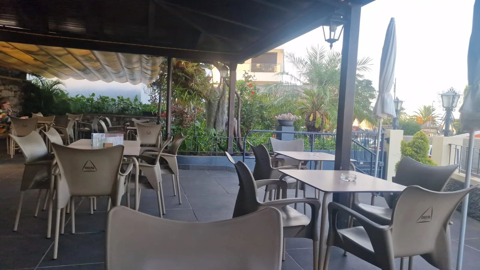 Covered terrace at Bar Rodrigues in Caniço de Baixo, with Delta chairs, tables and tropical garden planting