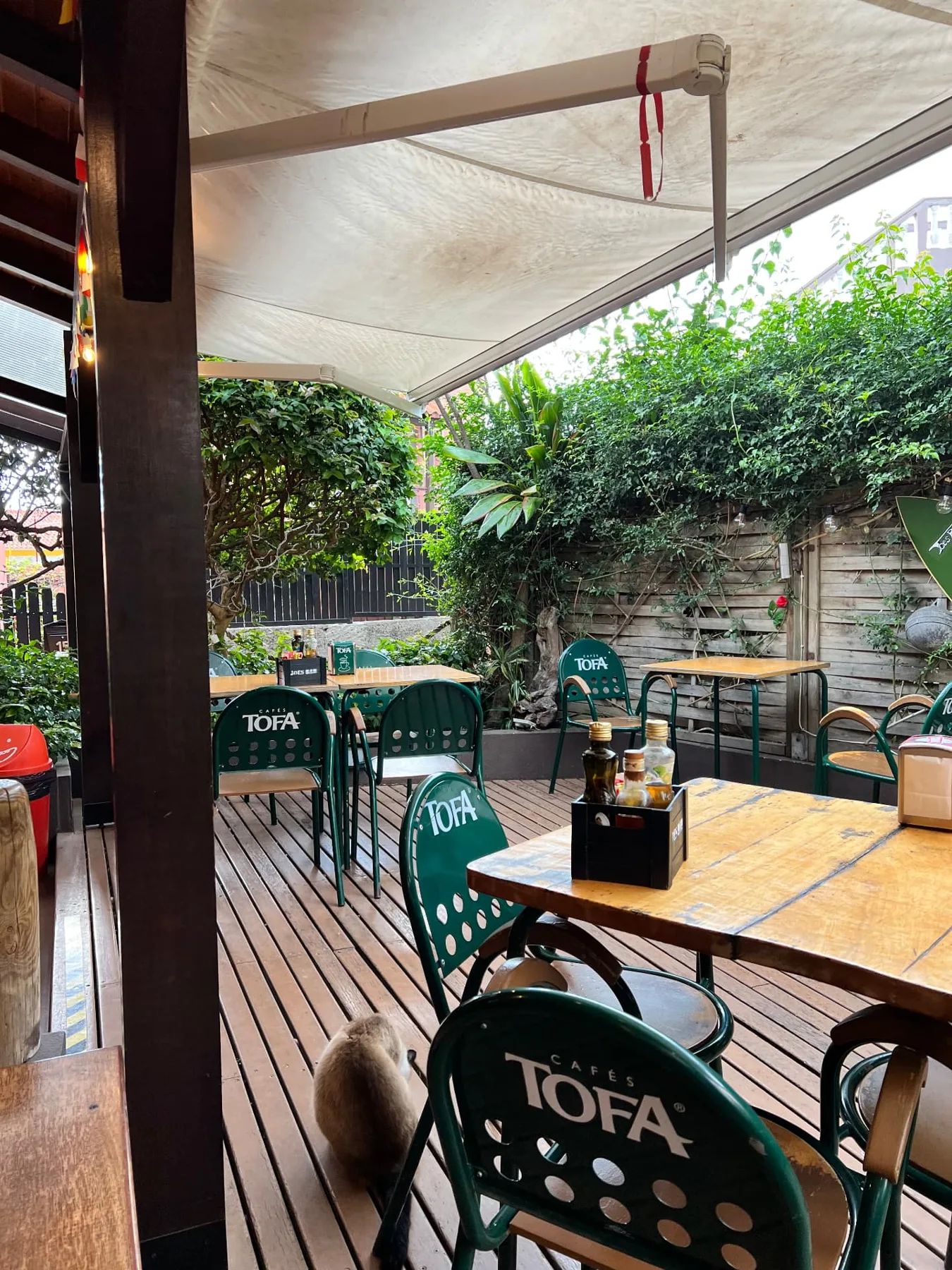 Shaded wooden deck at Joe's Bar with tables and green garden