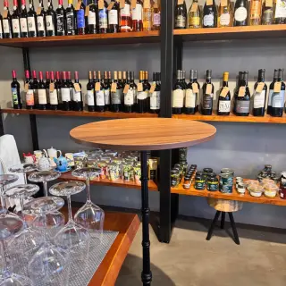 Shelves of Portuguese wines behind a tall wooden tasting table at Just Add Vino in Caniço