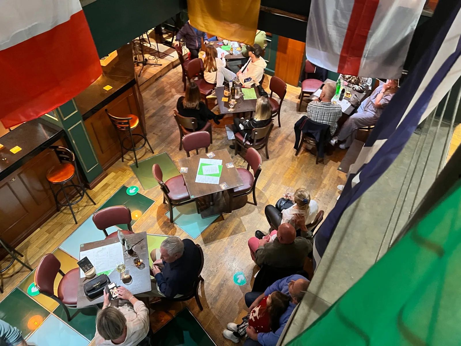 Olhando para baixo a partir do mezanino do Moynihans Irish Bar, no Funchal, com bandeiras a pairar por cima e os clientes a beberem nas mesas lá em baixo
