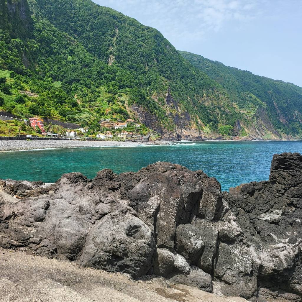 Seixal beach and the green volcanic cliffs of Madeira's north coast seen from the lava rocks at Praia da Laje