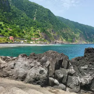 Seixal beach and the green volcanic cliffs of Madeira's north coast seen from the lava rocks at Praia da Laje