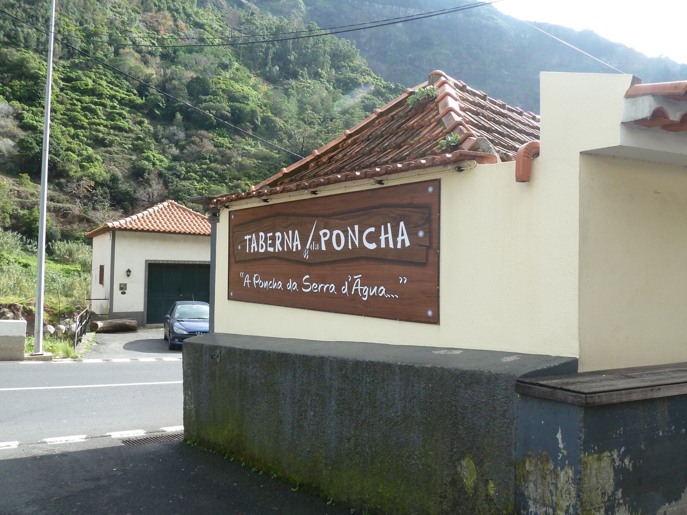 Wooden Taberna da Poncha sign on a cream wall beneath a tiled roof
