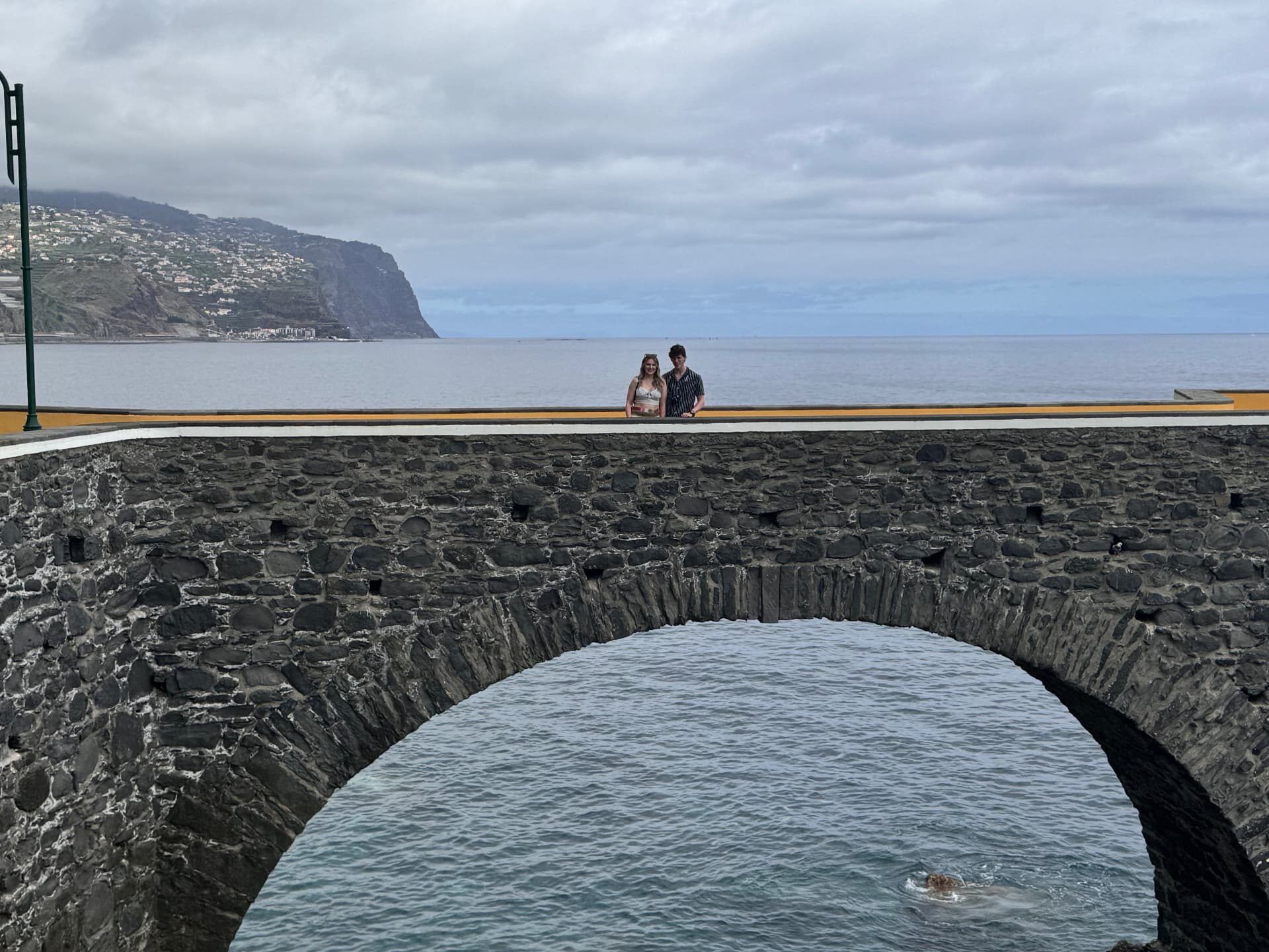 The old stone sea bridge at Praia da Ponta do Sol with Cabo Girão behind