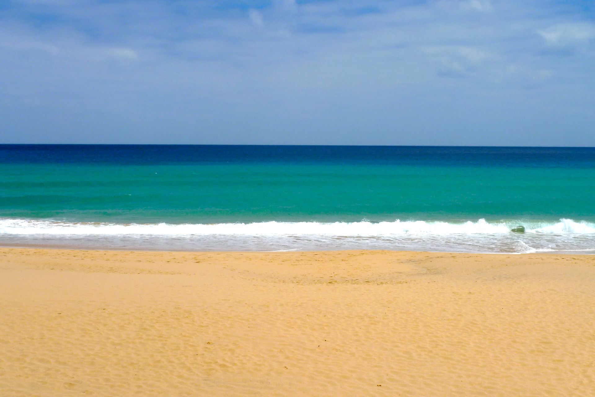Golden sand and turquoise Atlantic water at Porto Santo beach on a clear day.