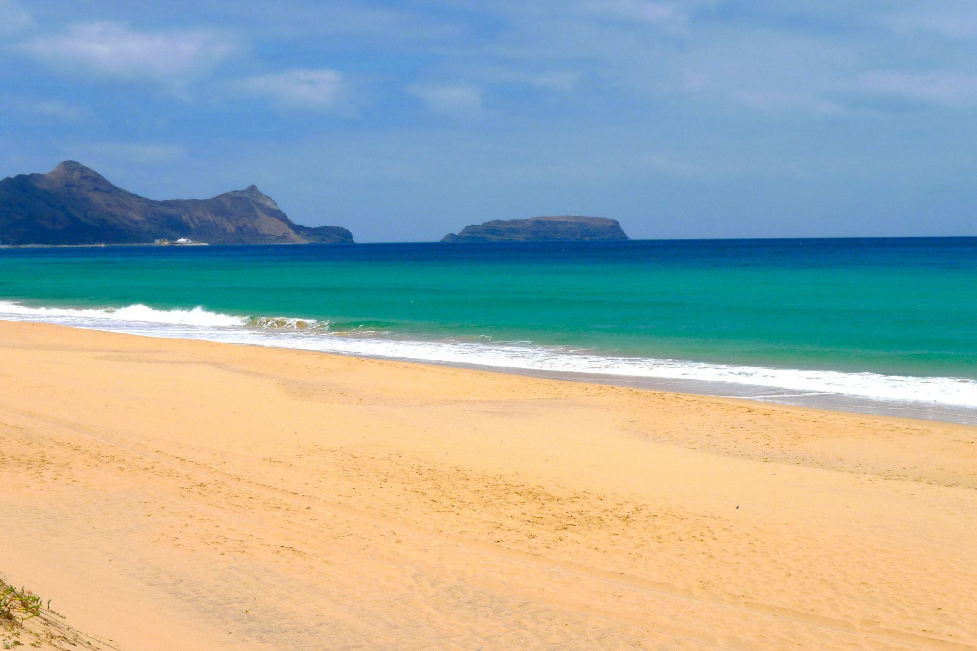 Golden sand and turquoise water at Porto Santo beach with the Ilhéu de Baixo islet on the horizon