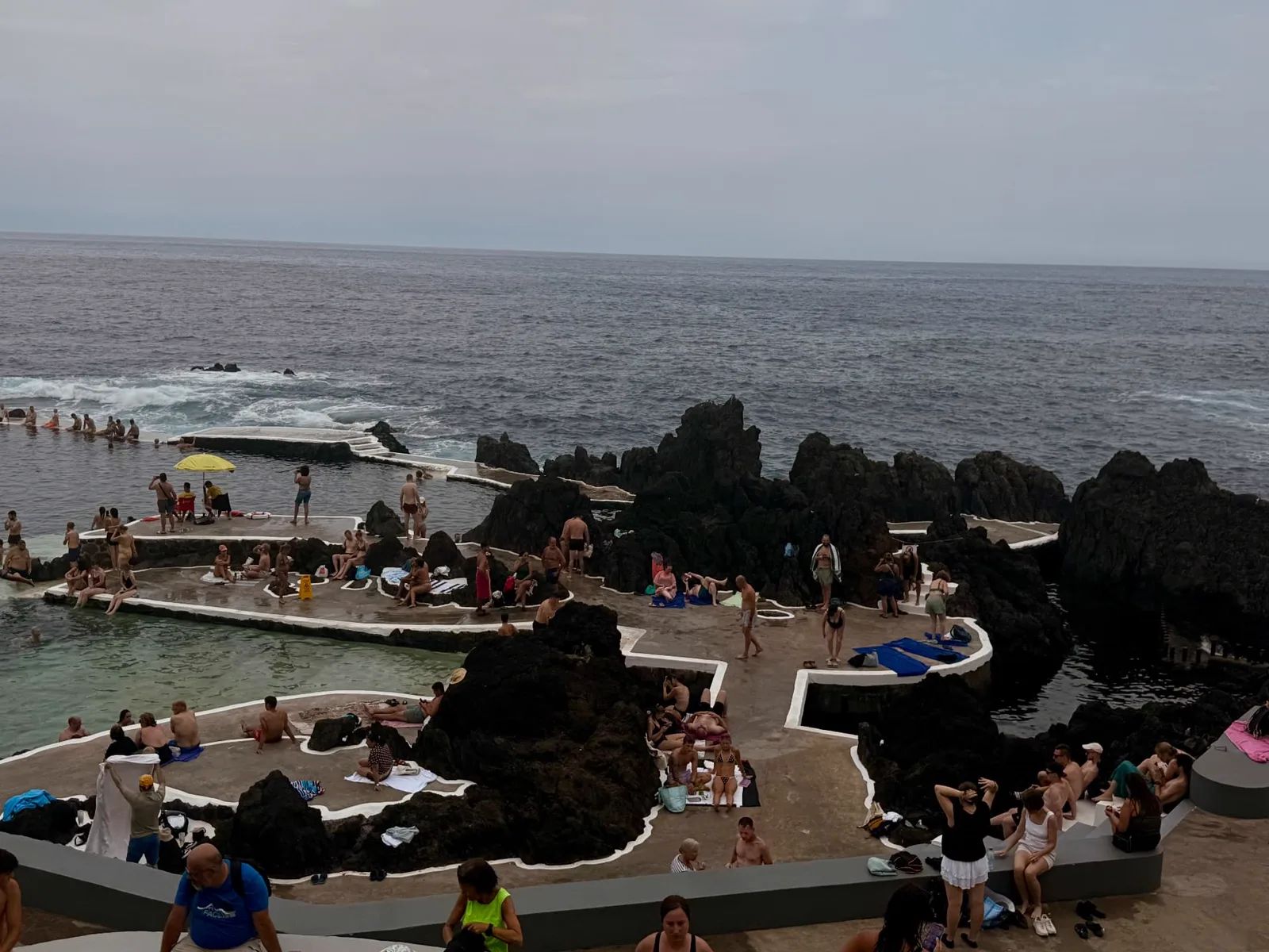 Sunbathing terraces between black lava rocks at the Porto Moniz natural pools