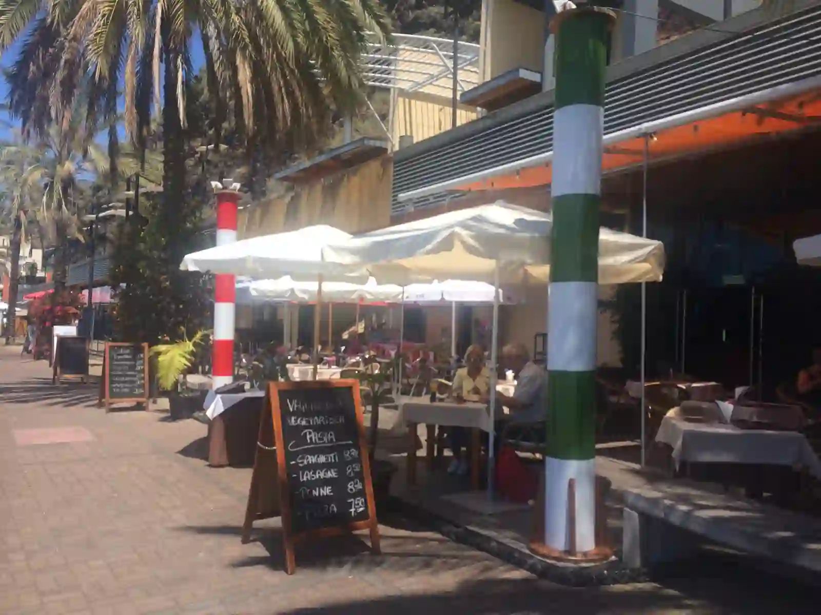 Café terraces and palm trees on the promenade at Praia da Calheta