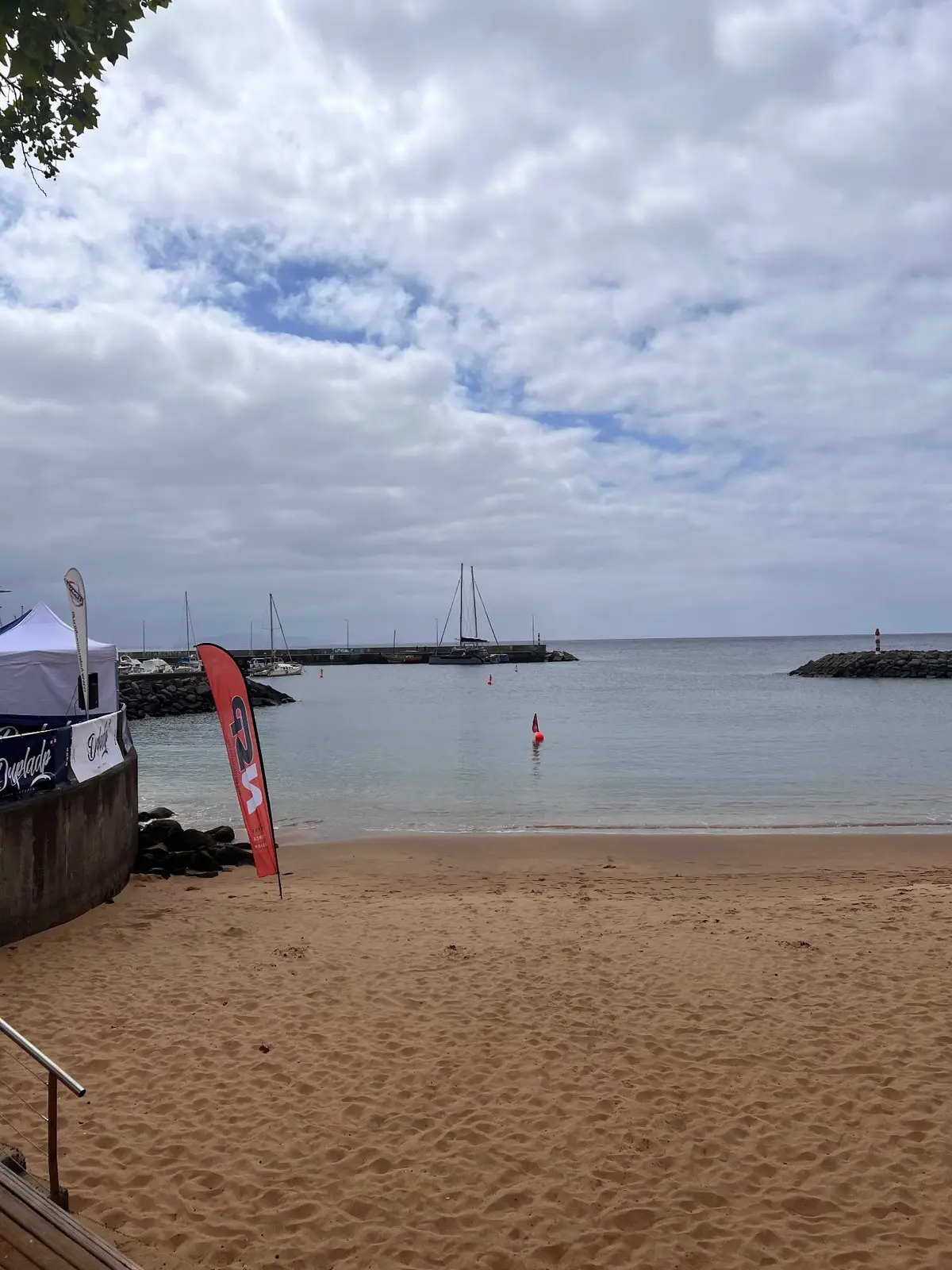 Calm water inside the breakwaters at Praia de Machico with swimming buoys and boats, Madeira