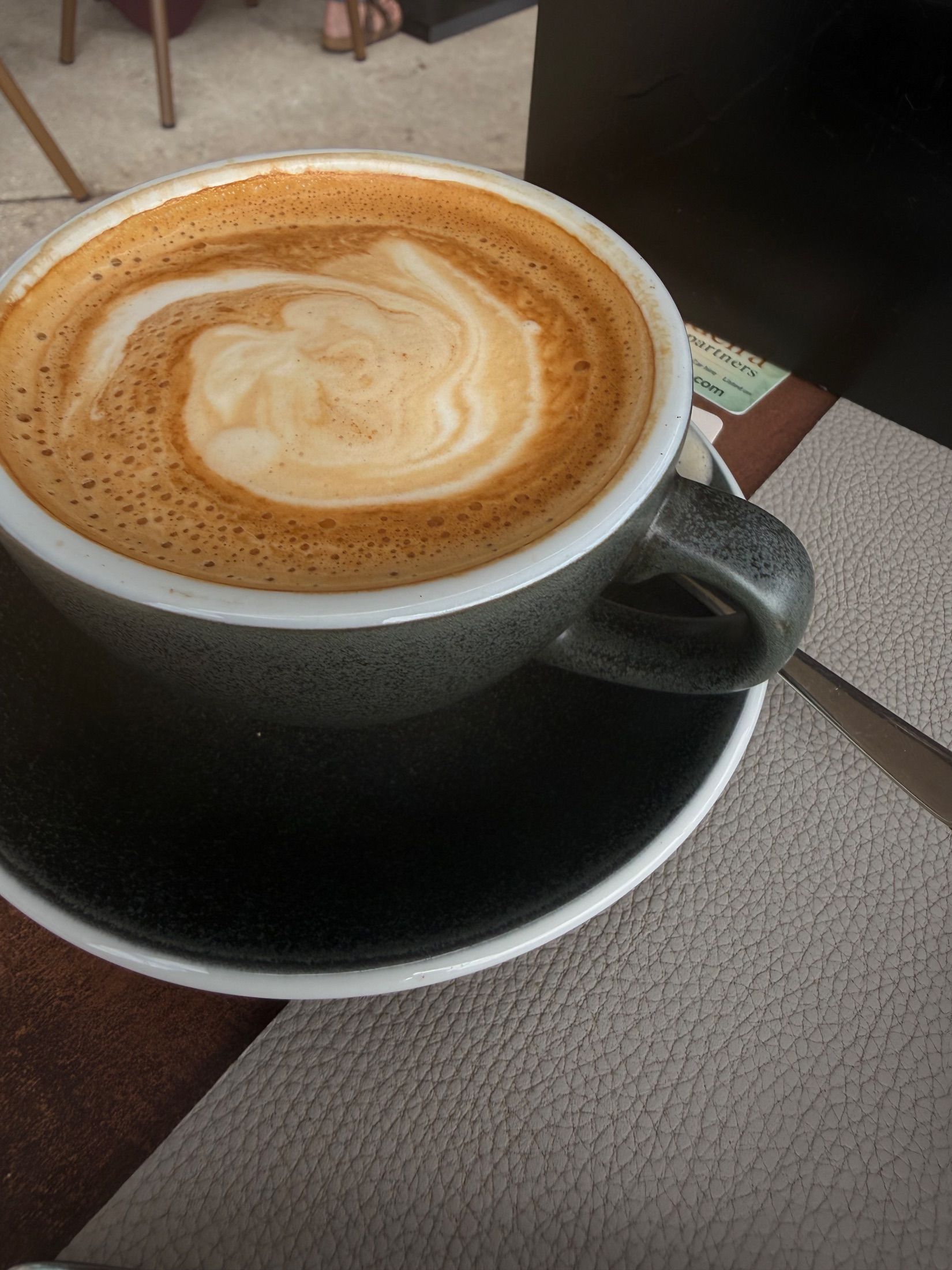 Coffee with milk foam in a grey ceramic cup on a matching saucer