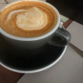 Coffee with milk foam in a grey ceramic cup on a matching saucer
