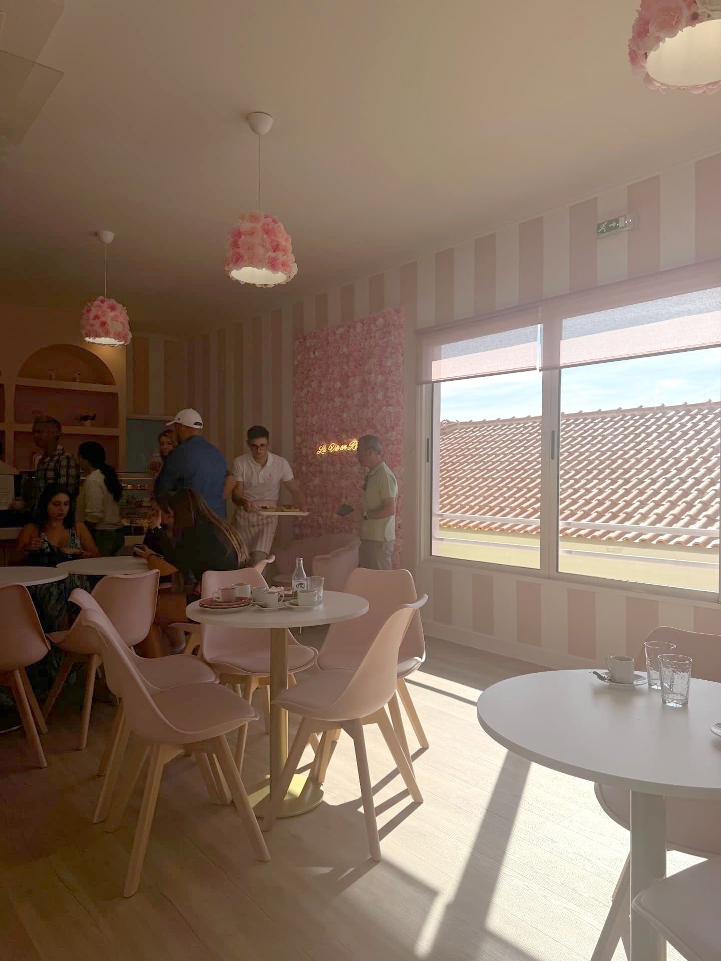Pink striped café interior at La Vie en Rose, Caniço de Baixo, with rose lampshades and a view over tiled roofs