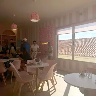 Pink striped café interior at La Vie en Rose, Caniço de Baixo, with rose lampshades and a view over tiled roofs