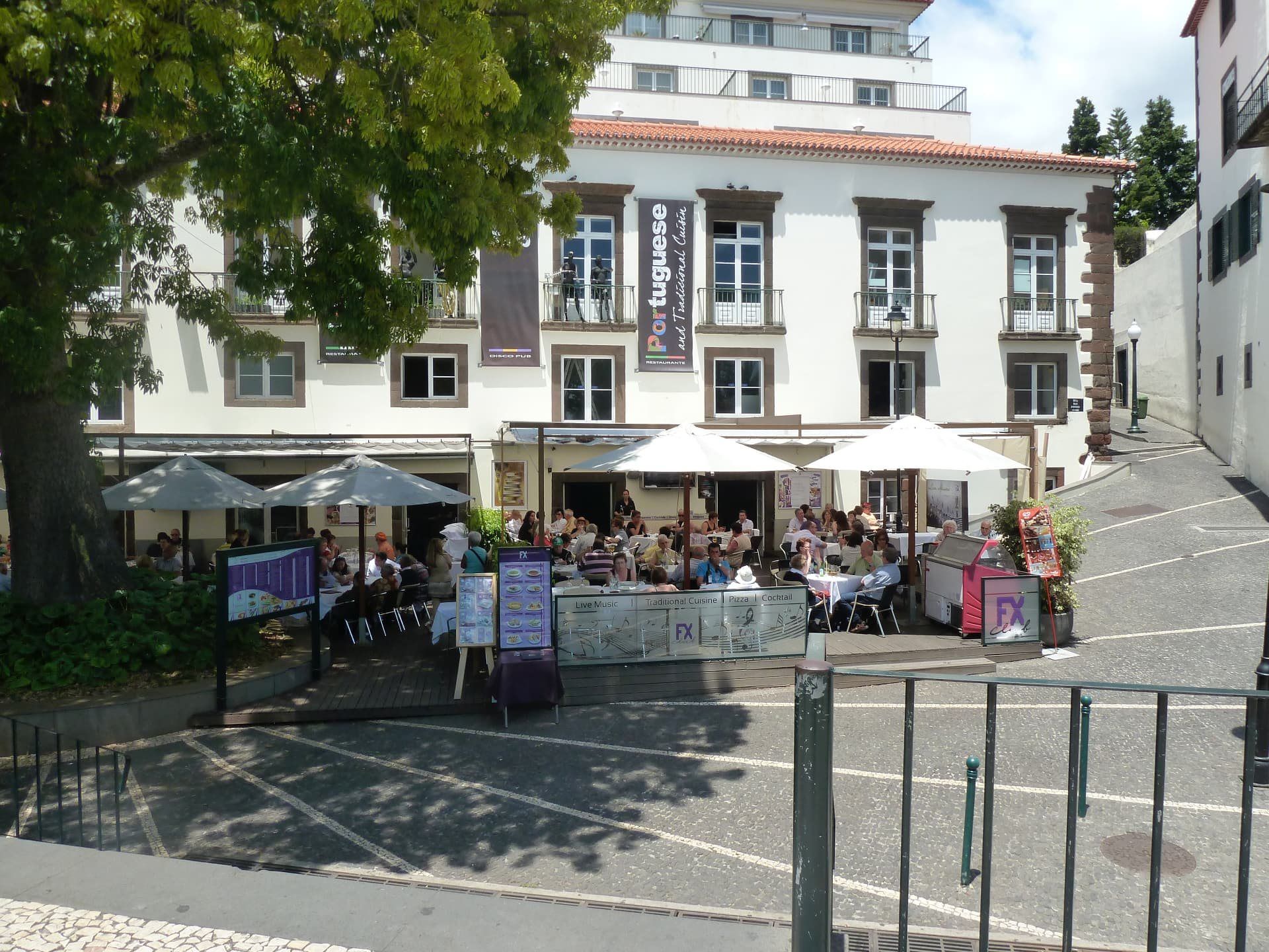 Restaurant terrace and plaza beside a historic Madeira building.