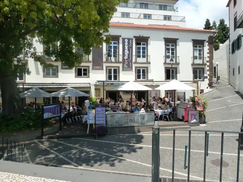 Restaurant terrace and plaza beside a historic Madeira building.