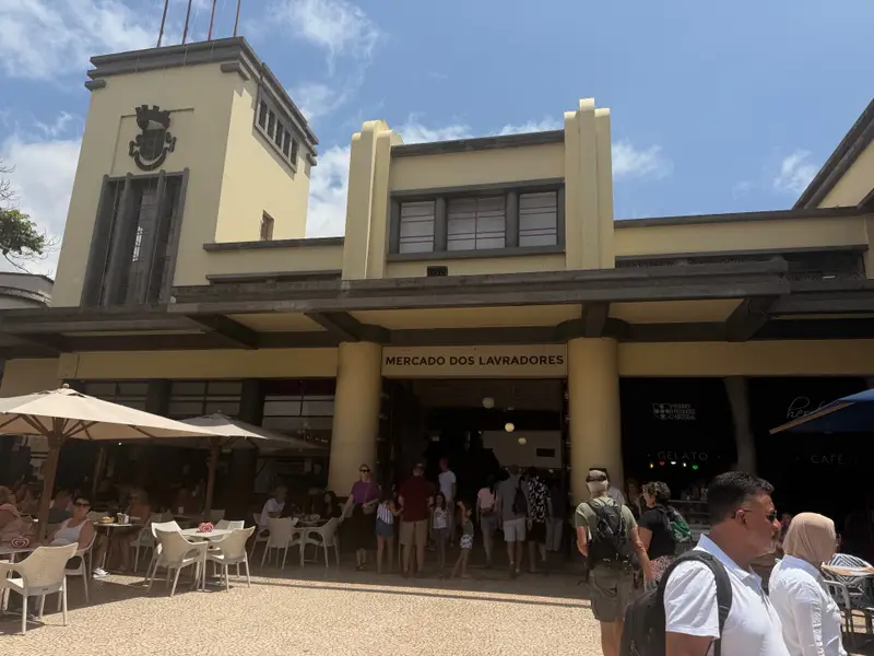 Art Deco facade and tower of Mercado dos Lavradores, Funchal, with cafe umbrellas below.