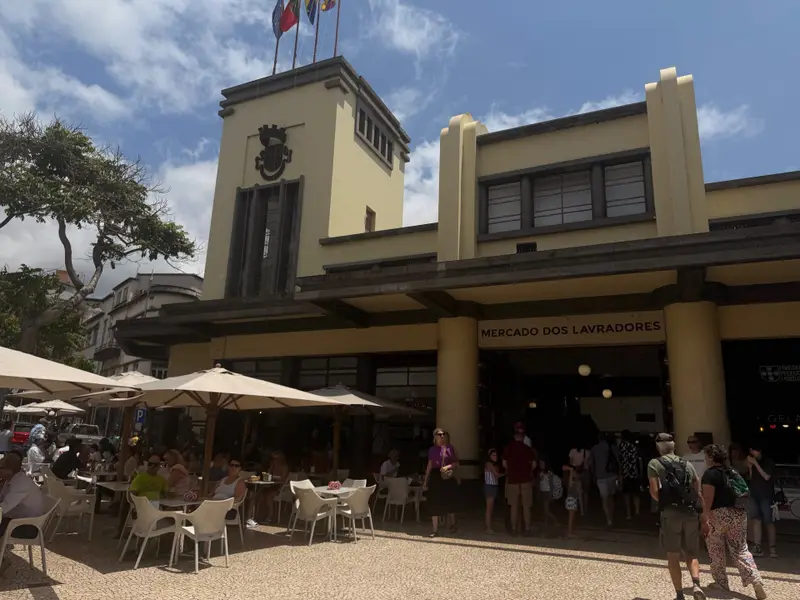 Mercado dos Lavradores exterior with flags on the tower, cafe terraces and shoppers, Funchal.