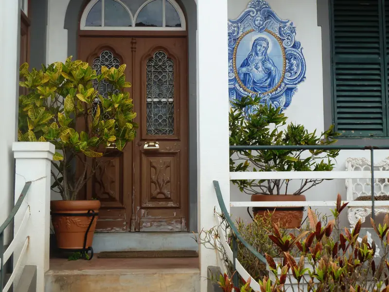 Traditional Madeira doorway with carved wooden doors and blue-and-white religious tiles.