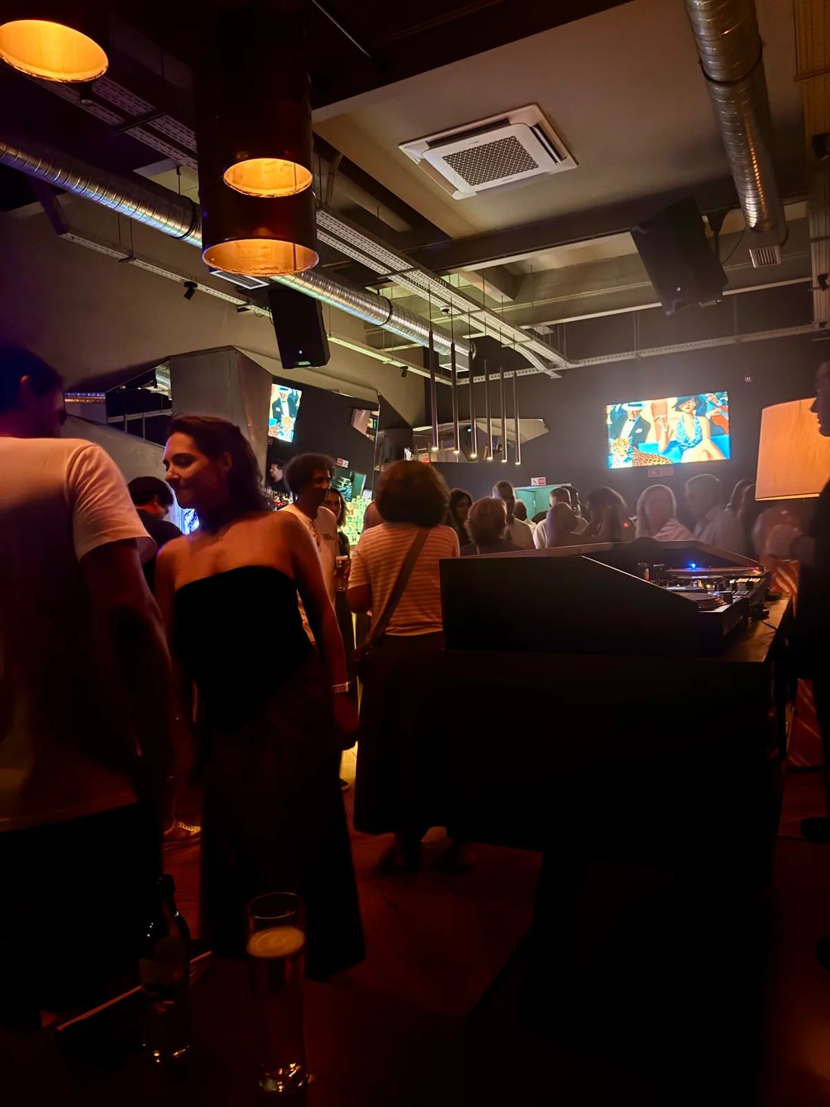 Busy night inside Groovy in Funchal, with a DJ booth, warm pendant lights and video screens