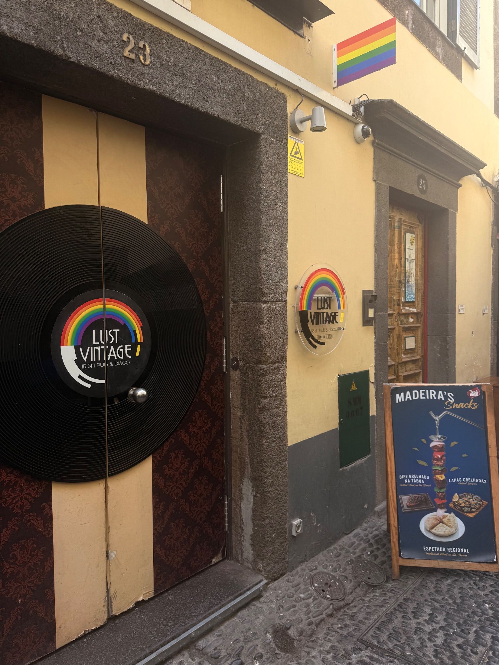 Lust Vintage entrance with vinyl record decoration and rainbow flag on a yellow façade