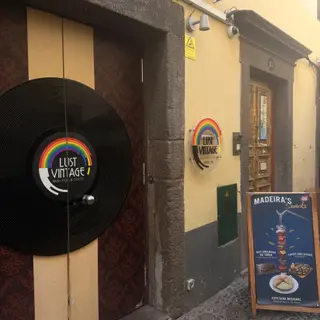 Lust Vintage entrance with vinyl record decoration and rainbow flag on a yellow façade