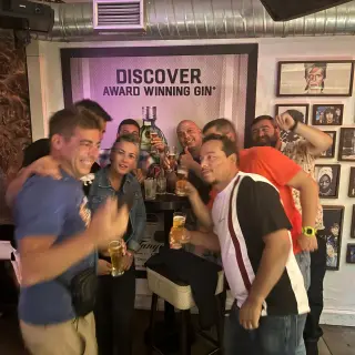A group raising drinks inside Lust Vintage in Funchal, beside a wall of framed music-legend photos