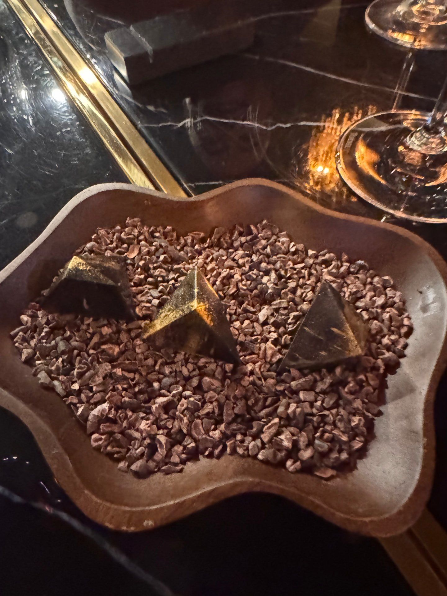 Petit fours em forma de pirâmide de chocolate servidos sobre grãos de cacau no restaurante Audax, no Funchal