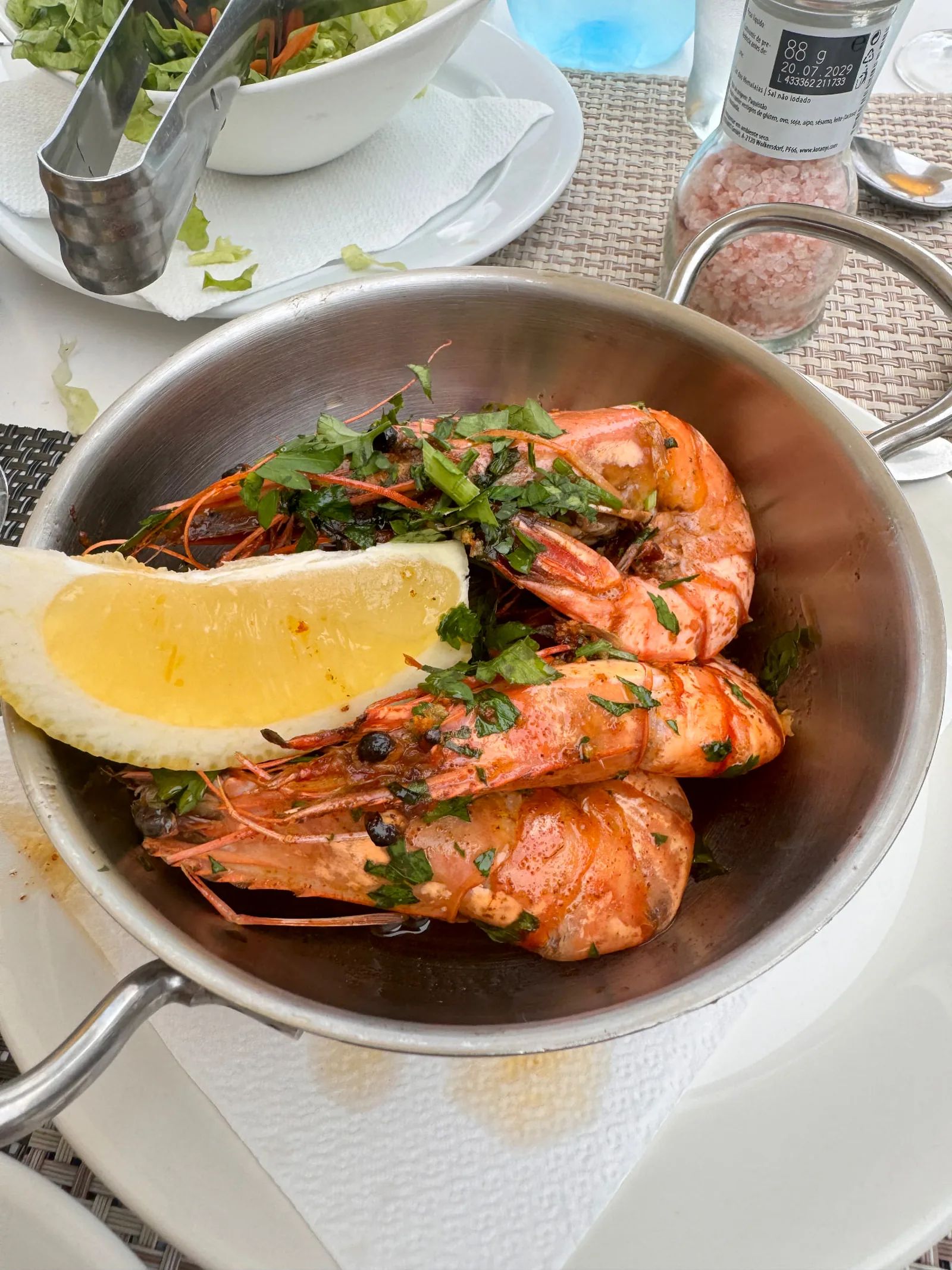 Pan of large grilled prawns with coriander, lemon and pepper sauce on a table at Bar Restaurante O Mero in Garajau