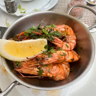 Pan of large grilled prawns with coriander, lemon and pepper sauce on a table at Bar Restaurante O Mero in Garajau