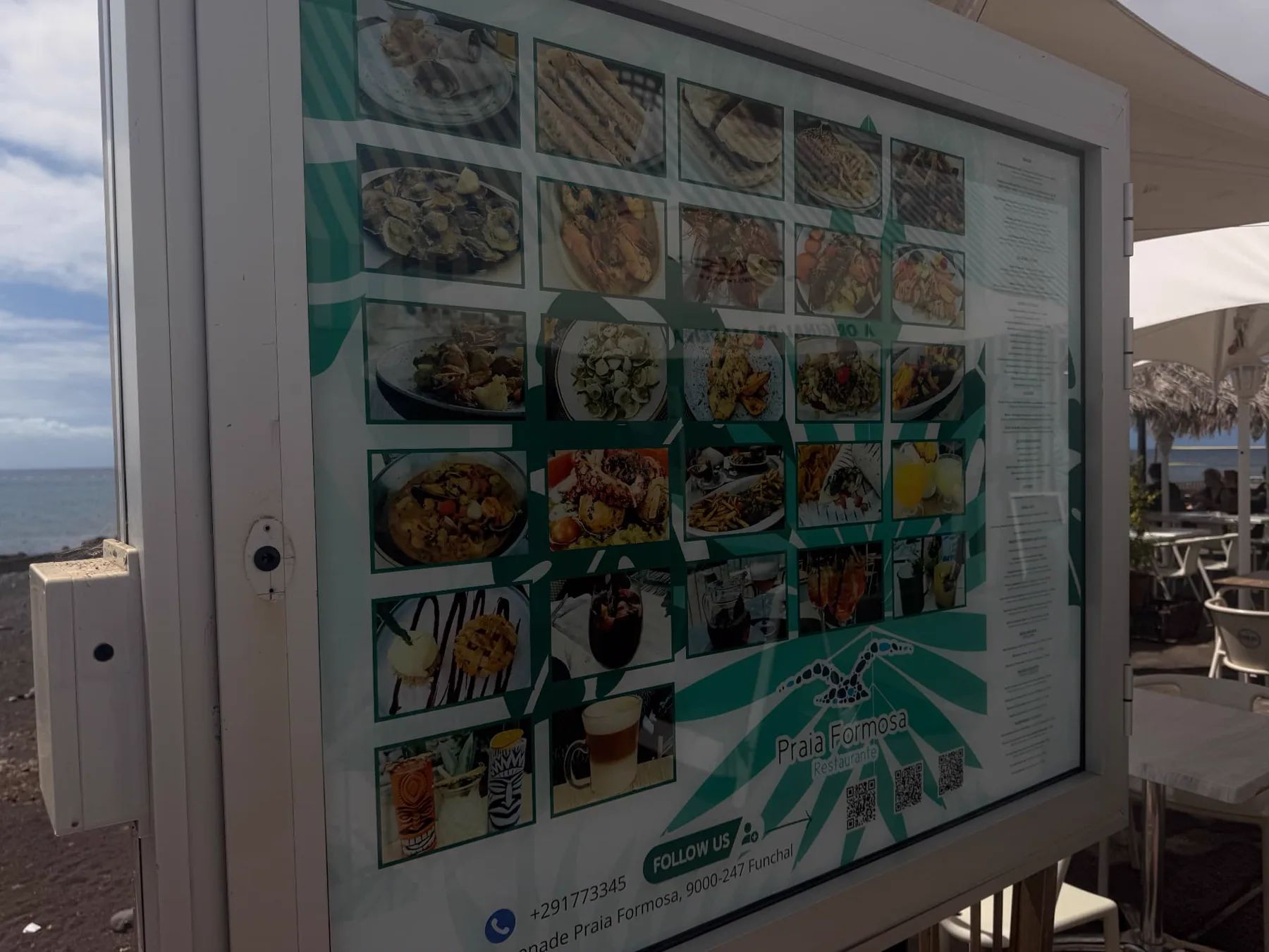 Food and drink picture menu outside Restaurante Praia Formosa, with the terrace and sea behind.