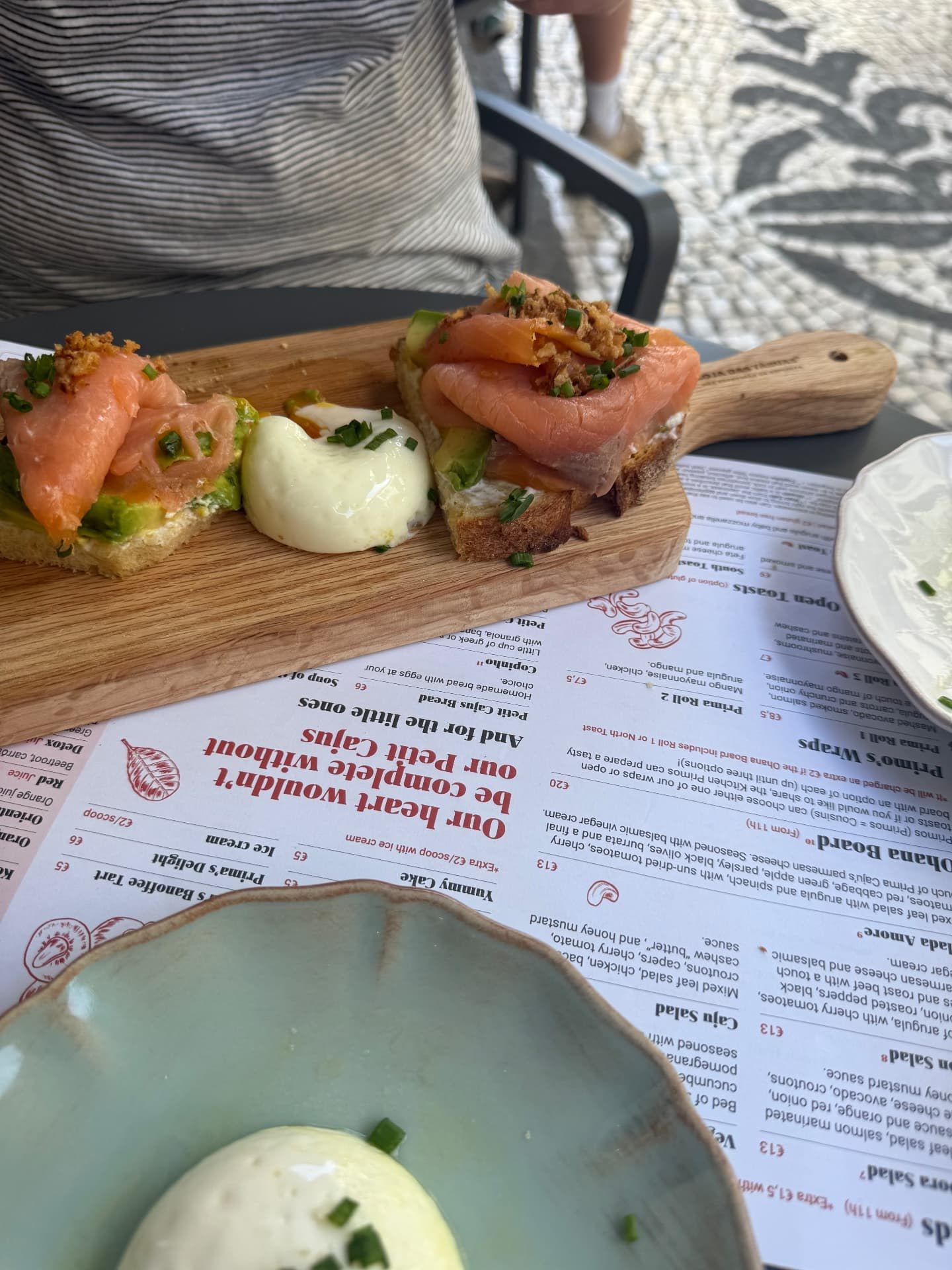 Smoked salmon and avocado sourdough toasts with a poached egg served on a wooden board at Prima Caju brunch cafe in Funchal, Madeira