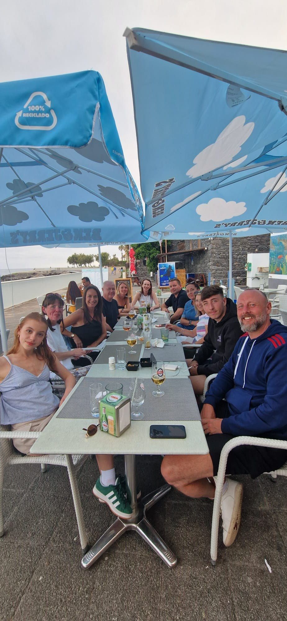 A group of friends dining together on the seafront terrace of Restaurante Praia dos Reis Magos in Canico de Baixo, Madeira