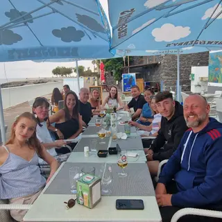 A group of friends dining together on the seafront terrace of Restaurante Praia dos Reis Magos in Canico de Baixo, Madeira