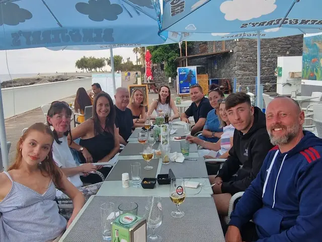 A group of friends dining together on the seafront terrace of Restaurante Praia dos Reis Magos in Canico de Baixo, Madeira