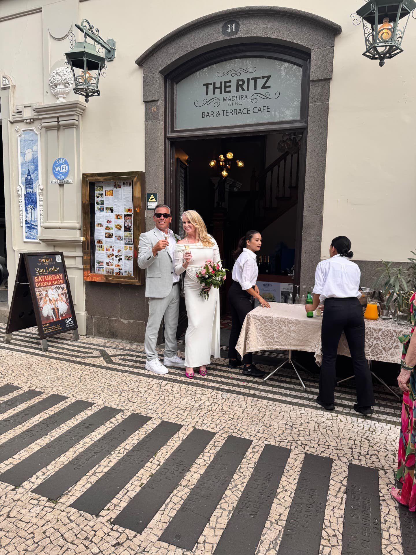 Os noivos com champanhe à entrada do The Ritz Madeira durante a celebração do seu casamento