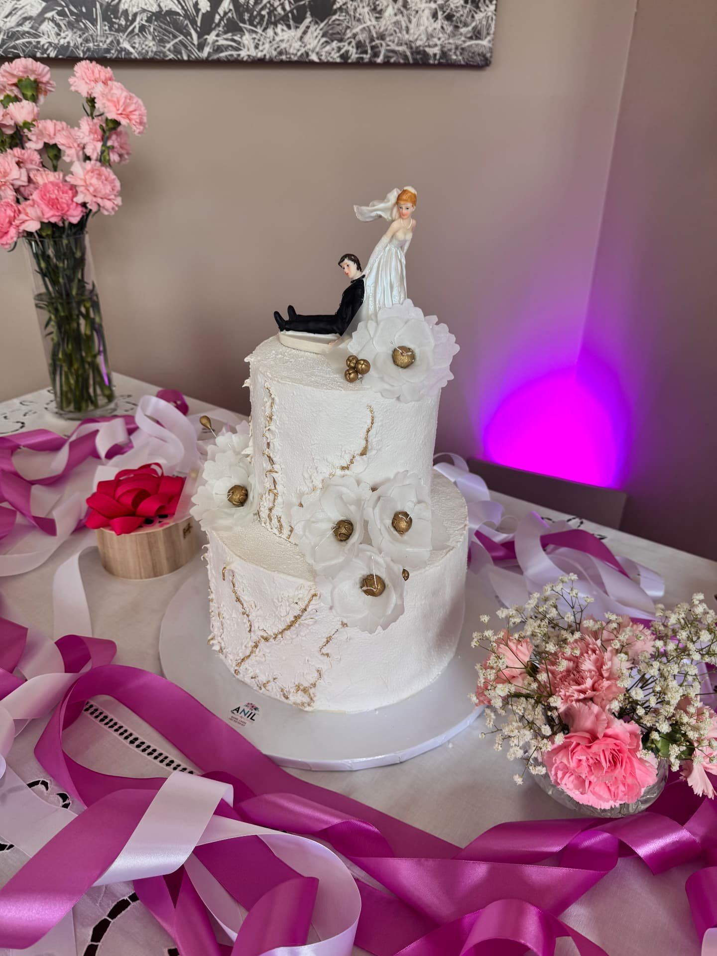 Bolo de casamento branco de dois andares, com flores de açúcar e uma figura dos noivos no topo, numa receção de casamento no Ritz Madeira