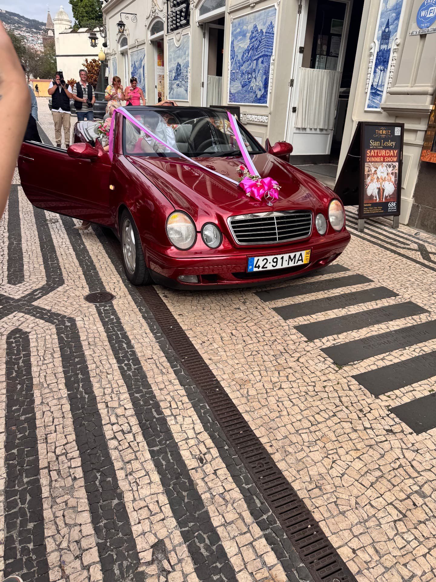 Carro de casamento com fitas cor-de-rosa à porta do The Ritz Madeira, na Rua da Alfândega, em Funchal, com pavimento em mosaico