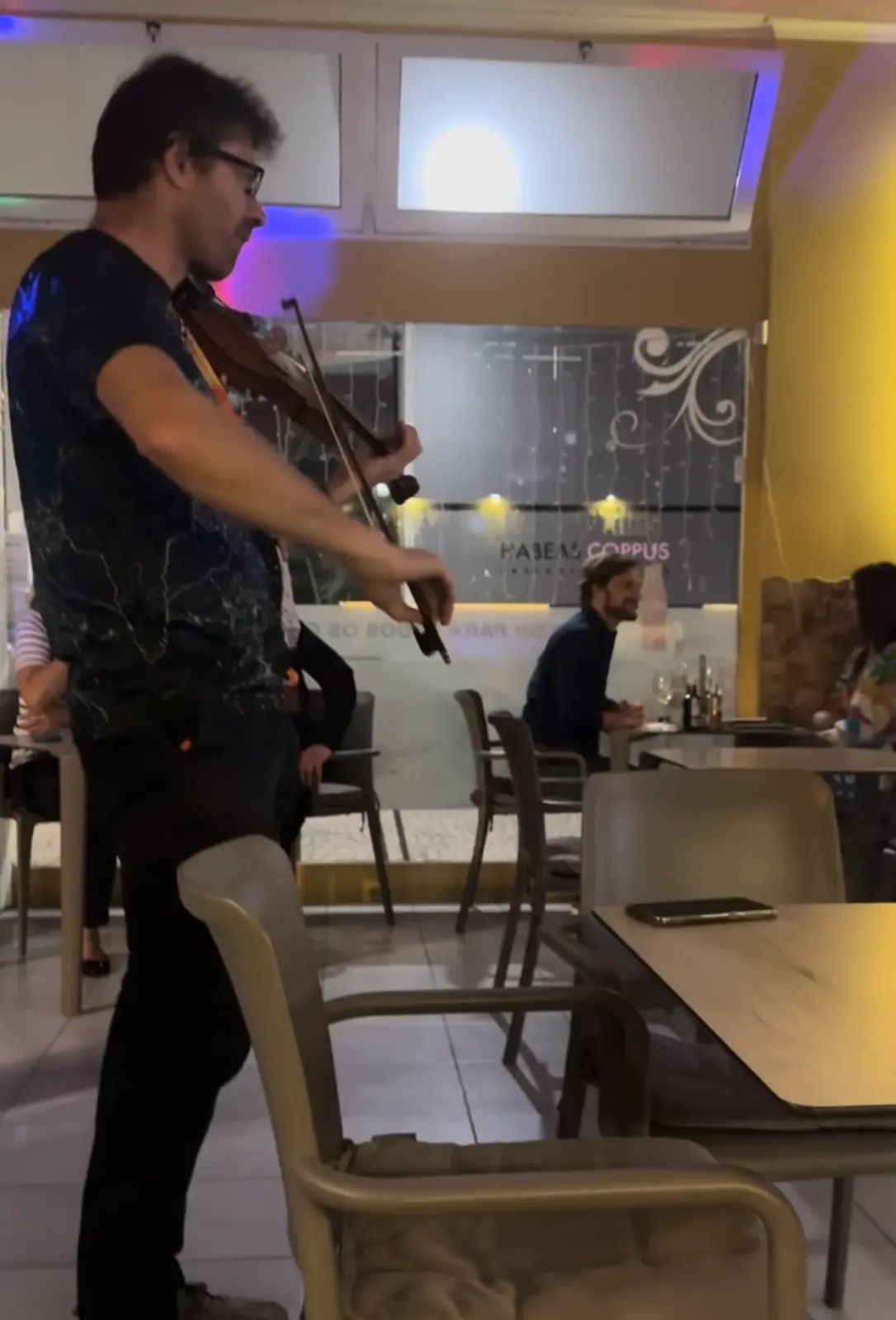 Violinist playing between the tables during a live music night at Snack Bar Maré in Caniço