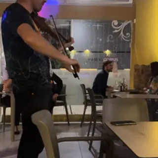 Violinist playing between the tables during a live music night at Snack Bar Maré in Caniço