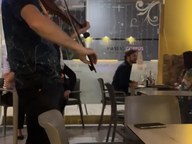 Violinist playing between the tables during a live music night at Snack Bar Maré in Caniço