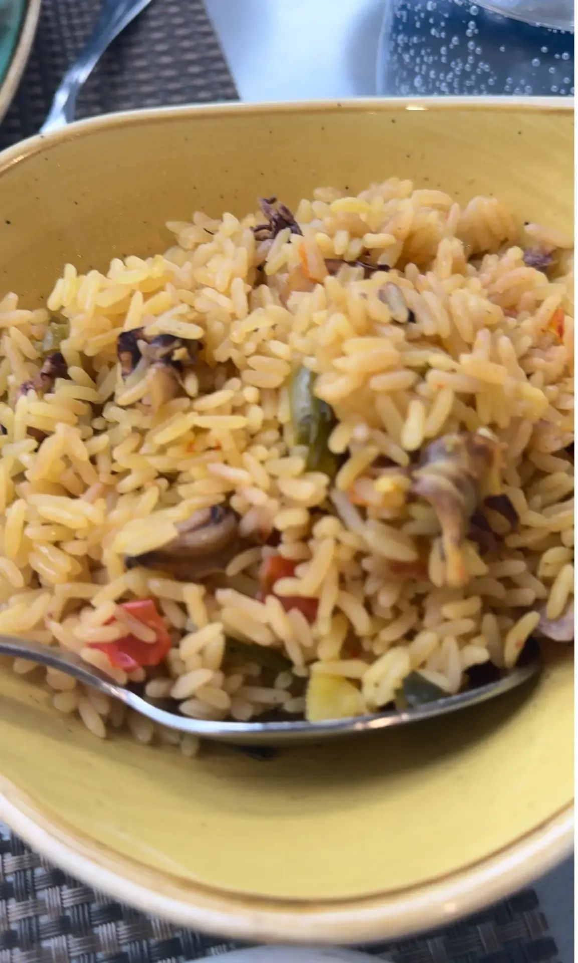 Bowl of seafood rice with squid, peppers and tomato served in a yellow bowl at A Traineira, Caniço
