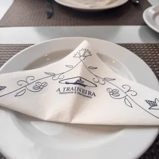 Table set with a folded A Traineira branded napkin on a white plate at the seafood restaurant in Caniço, Madeira