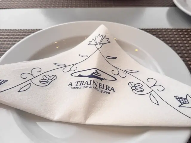 Table set with a folded A Traineira branded napkin on a white plate at the seafood restaurant in Caniço, Madeira