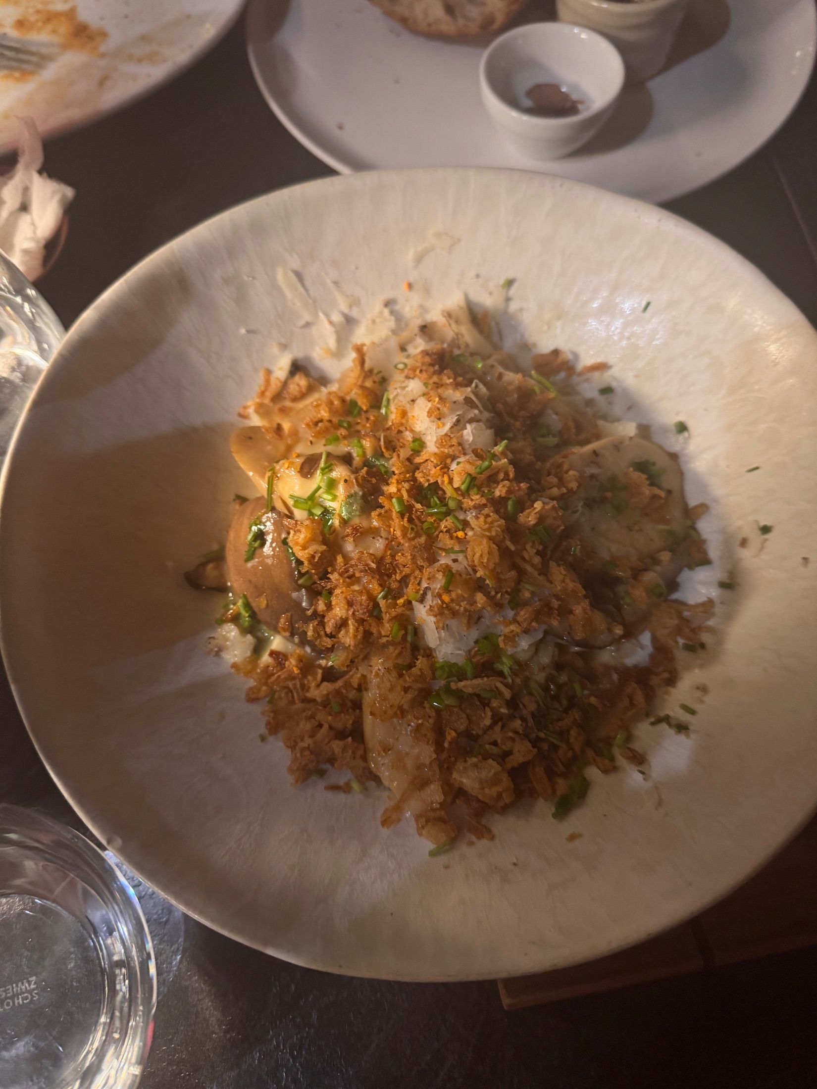Food topped with chopped herbs and golden flakes in a wide ceramic bowl