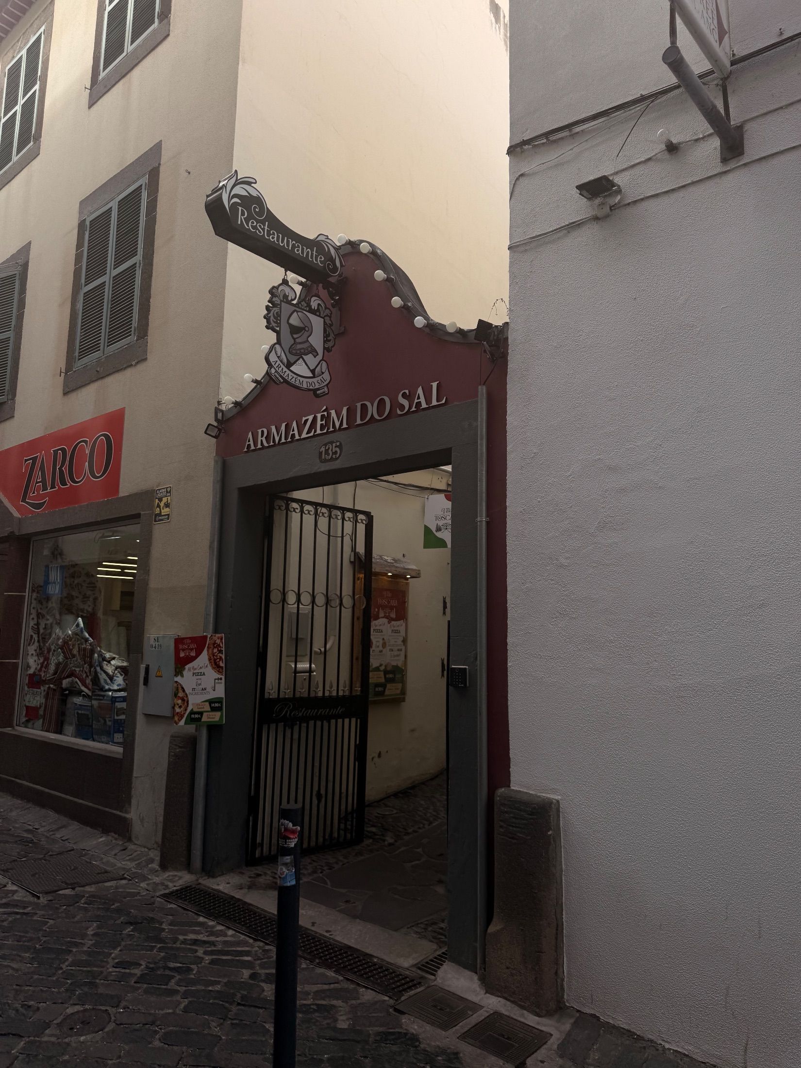Entrada do restaurante Armazém do Sal com letreiro decorativo e portão de ferro aberto