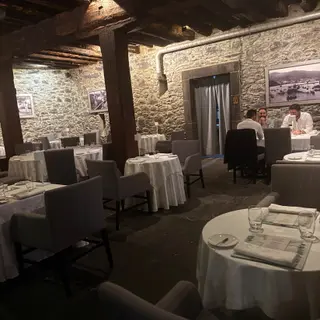 Restaurant dining room with stone walls, exposed wooden beams and white tablecloths