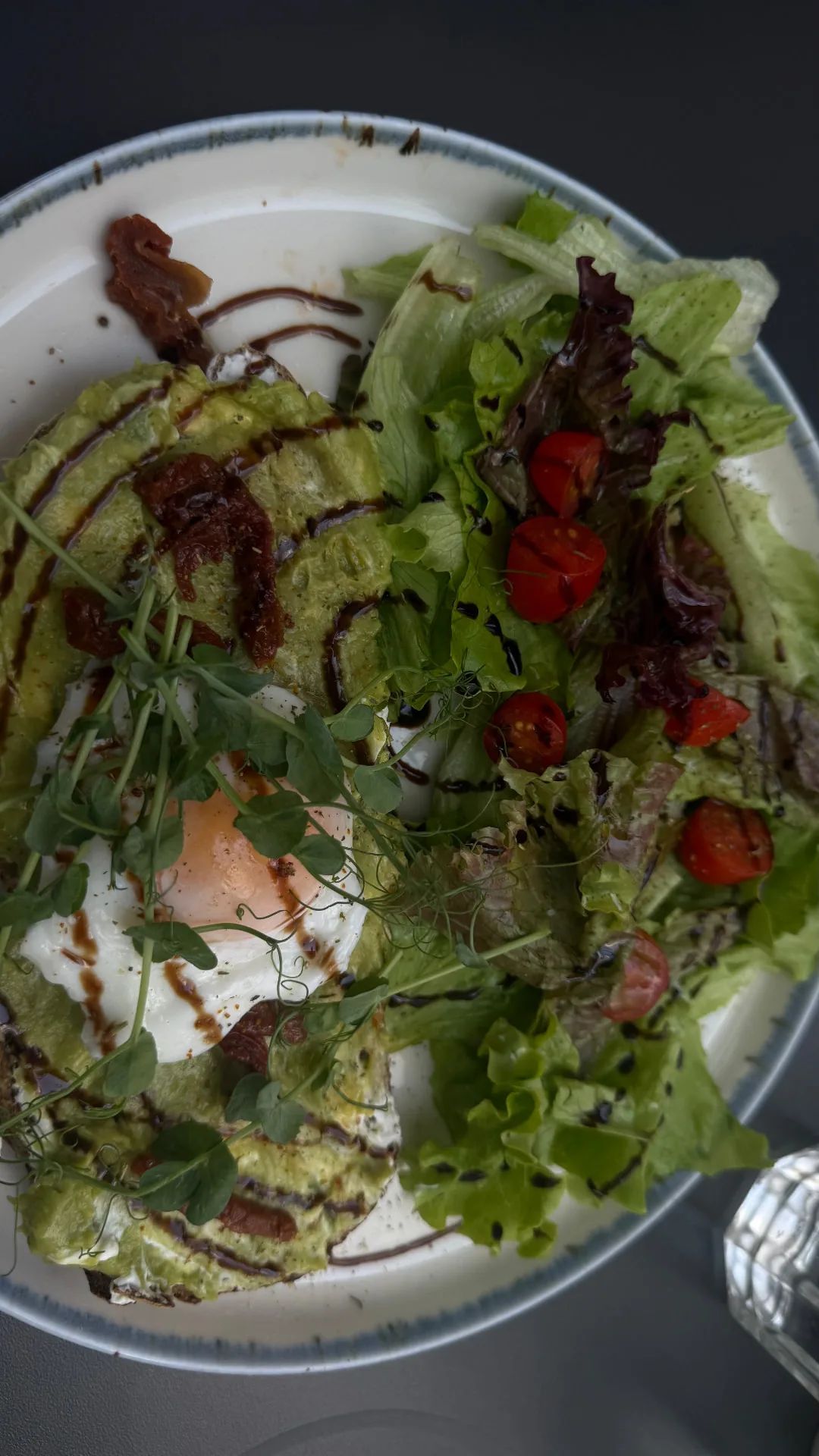 Avocado toast with a fried egg, pea shoots, sun-dried tomatoes and balsamic, with a side salad, at Brunchology