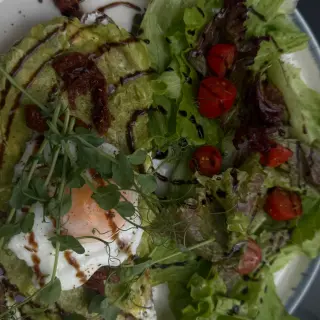 Avocado toast with a fried egg, pea shoots, sun-dried tomatoes and balsamic, with a side salad, at Brunchology