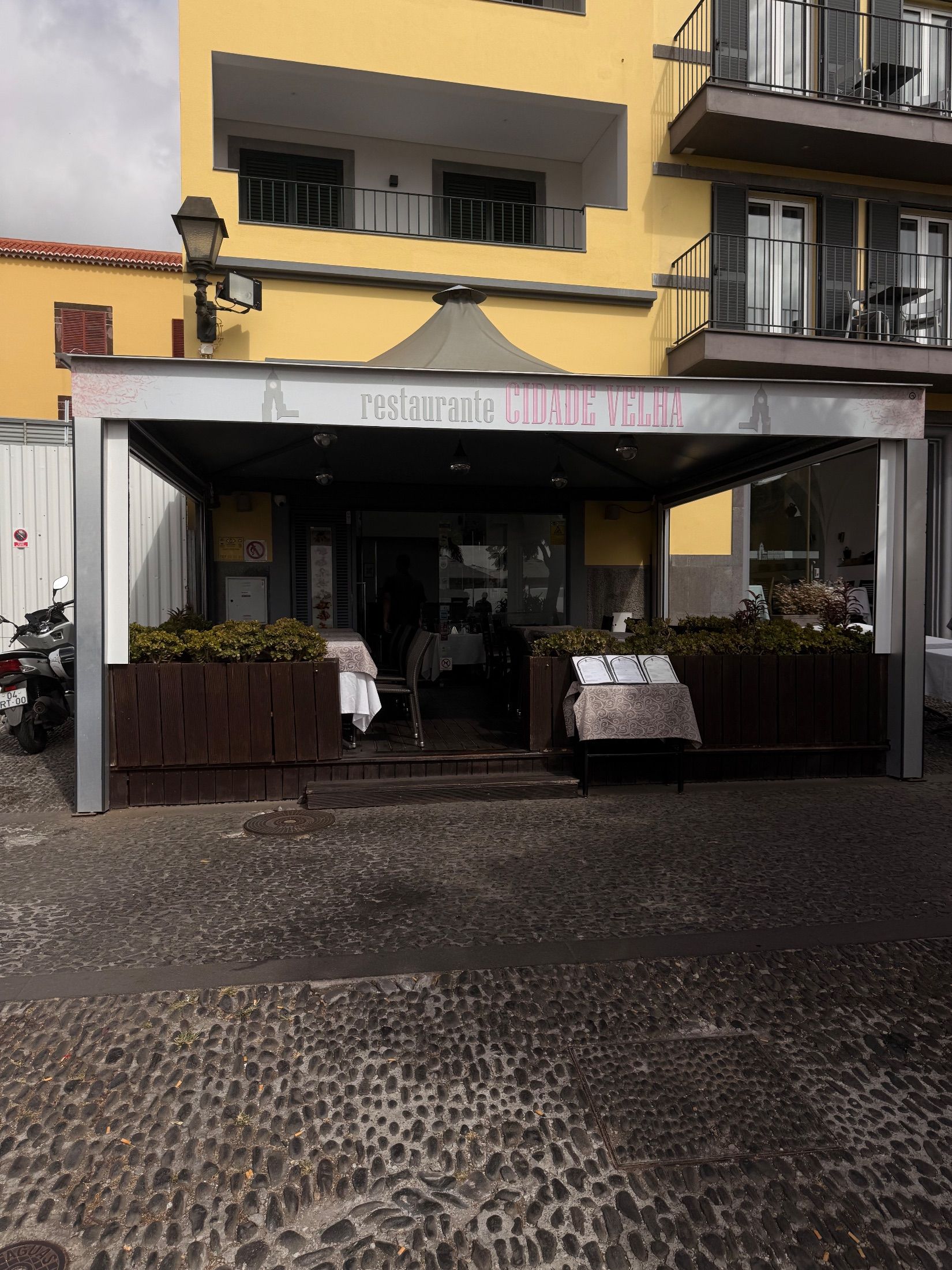 Cidade Velha restaurant with covered terrace, wooden planters and menus displayed outside